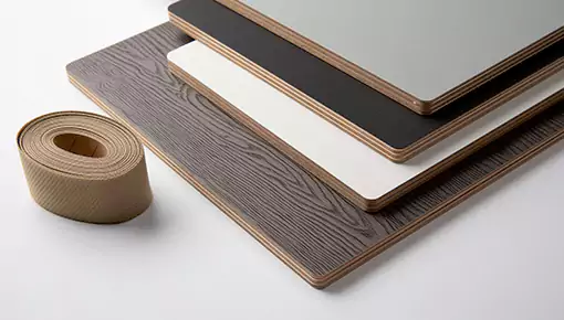 Four wooden boards are placed on a white table, with a roll of tape nearby—Fokis adhesive is suitable for bonding wood panels and edge banding.