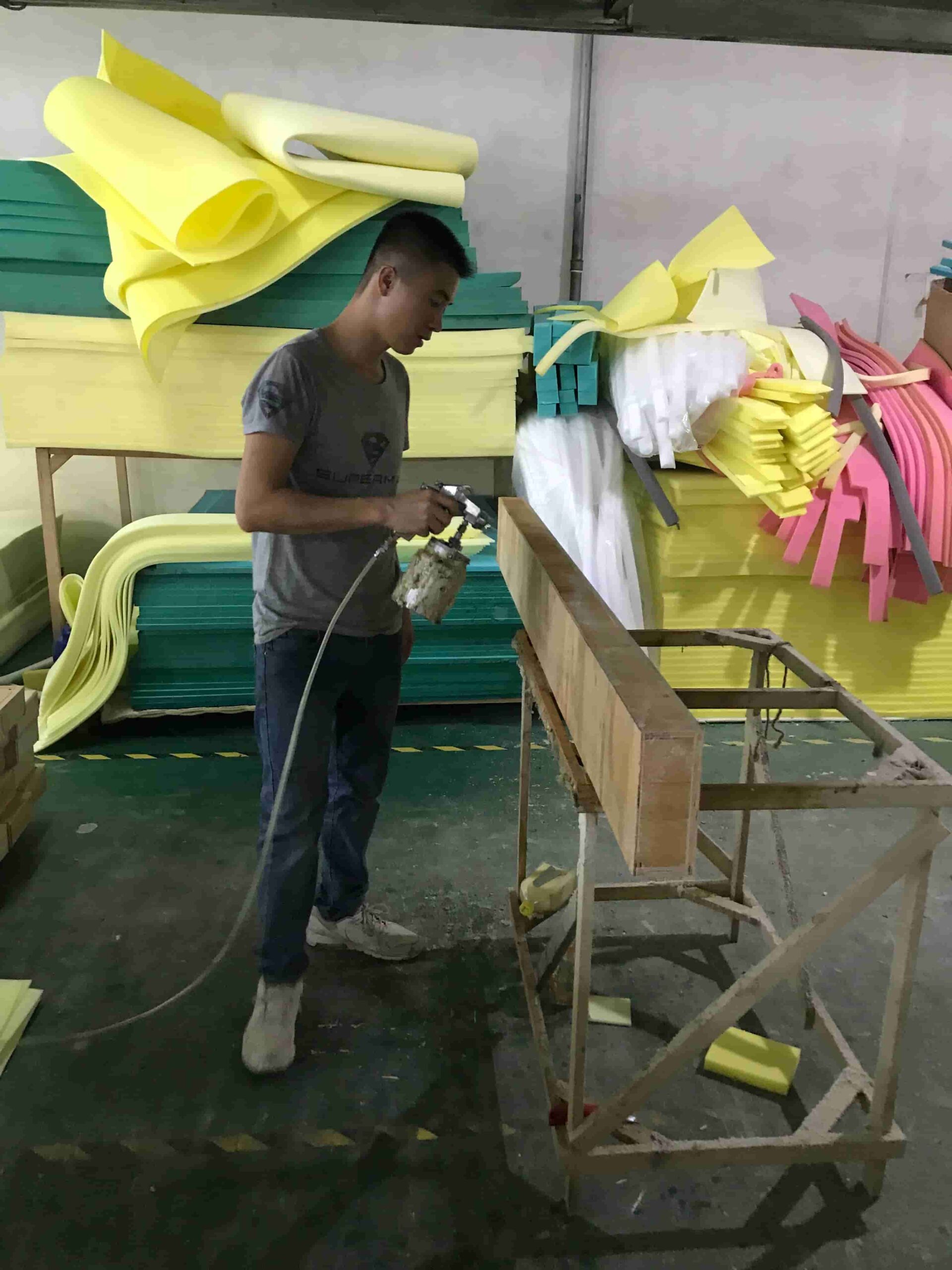Furniture factory uses Fokis adhesive to spray wooden frames A worker at a furniture factory uses a spray gun to spray Fokis adhesive onto wooden frames in a production workshop piled with furniture materials.